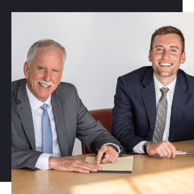 Father and son personal injury and disability lawyers sitting on desk.