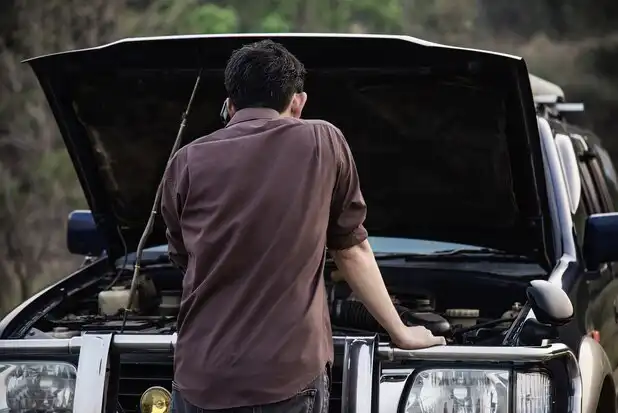 Car Accident Scene: Man Inspecting Engine Issue on the Road